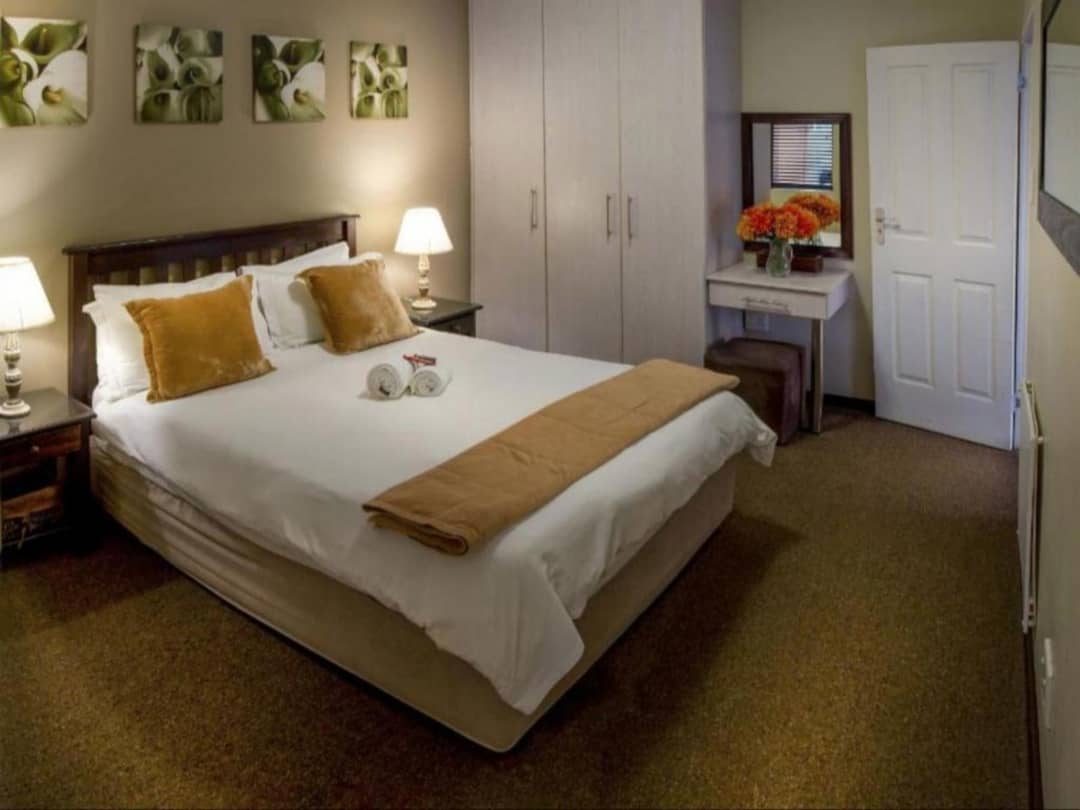 Double bed with gold throw, bedside lamps, and wardrobe nearby.