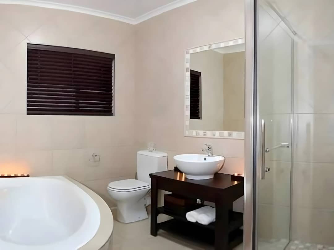Bathroom with round soaking tub, vessel sink, and glass shower.
