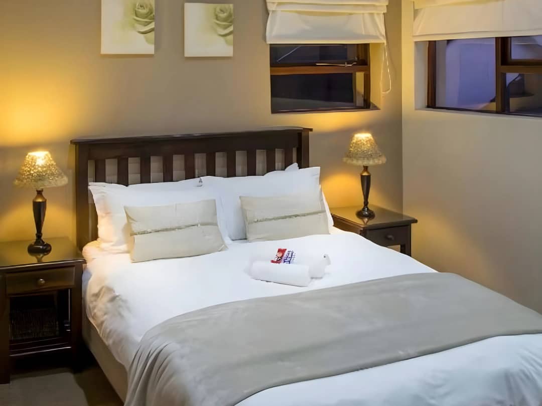 Bedroom with wooden headboard, bedside lamps, and folded towel decoration.