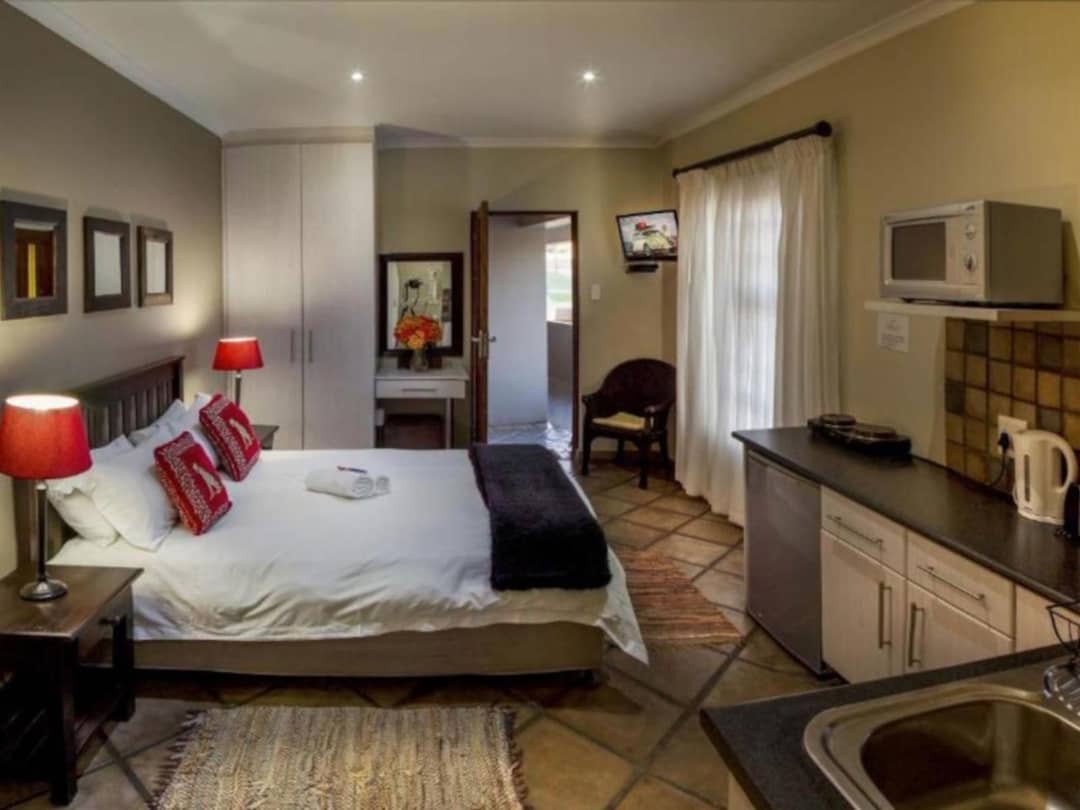 Studio room with double bed, red lamps, and kitchenette area.