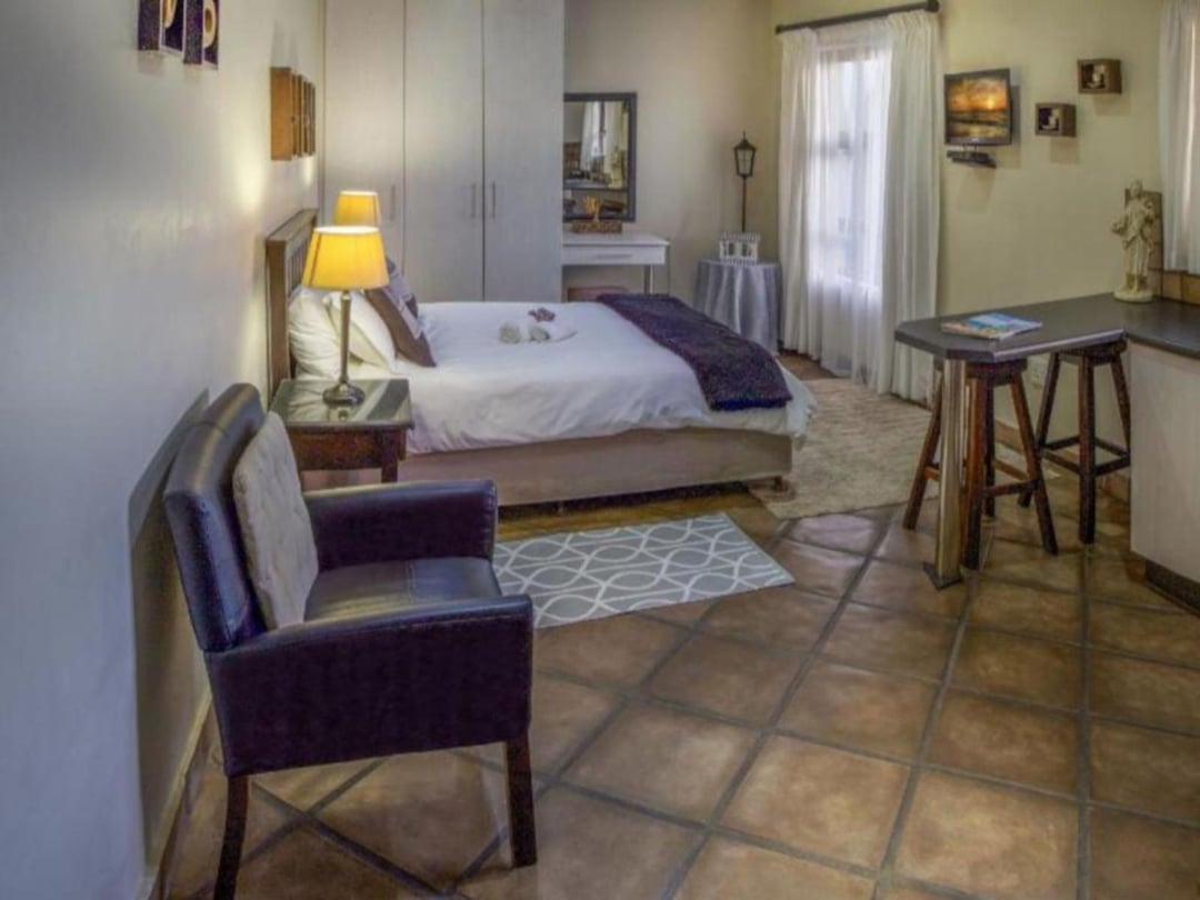 Tiled bedroom with leather armchair, bedside lamp, and small bar table.